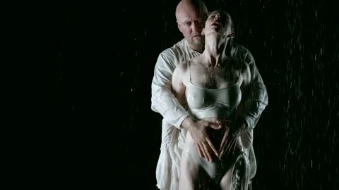 In this exciting scene on a black background in the rain, a bald man and his Stock Footage 274727609