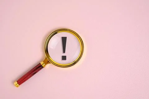 Exclamation mark under magnifying glass, on pink background. Stock Photos