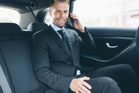 Executive businessman at the back of car using a mobile phone Stock Photos