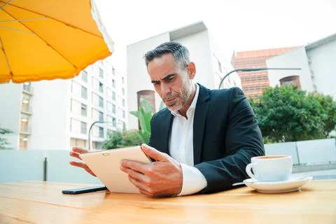 Executive businessman using tablet at outdoor cafe successful middle aged Stock Photos