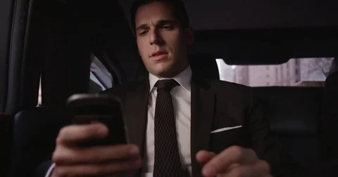An executive checks his phone in the back of a moving limo Stock Footage 73250966