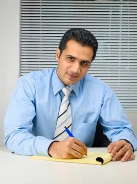 Executive looking at camera writing on notepad MR 779K Copyright: xVirenxD... Photos