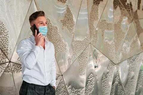 Executive man using a face mask while talking on the mobile phone outside the Stock Photos
