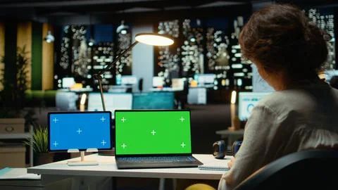 Executive manager at desk uses green screen on laptop and blue screen on tablet Stock Photos