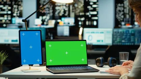 Executive manager at desk uses green screen on laptop and blue screen on tablet Stock Photos