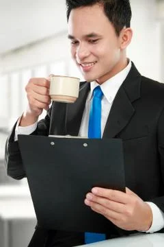 Executive reading a report while drinking Stock Photos