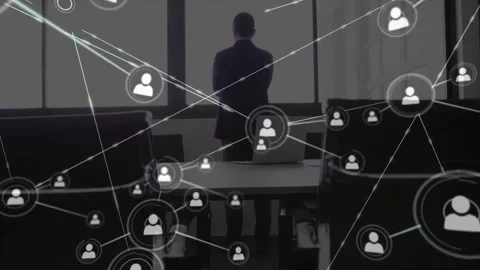 Executive standing at window watching user icon fading in on table, driving Stock Footage 327528059