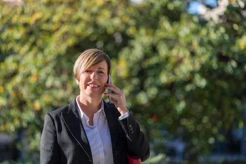 Executive talking on phone looking at camera on the street Stock Photos