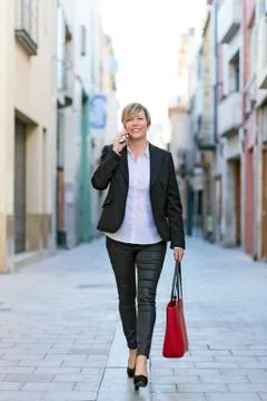 Executive talking on phone looking at camera walking on the stre Stock Photos