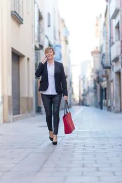Executive talking on phone looking at camera walking on the street Stock Photos