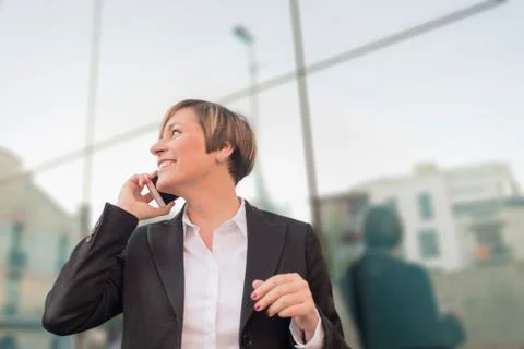 Executive talking on phone looking at camera on the street Stock Photos