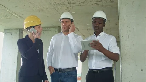 Executive team on construction site discussing project, using tablet, having Stock-Footage 82803934