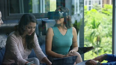 Executive using vr headset while colleagues discussing with each other in office Stock Footage 75452061