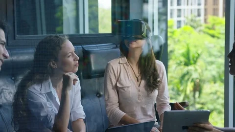 Executive using vr headset while colleagues discussing with each other in office Stock Footage 75452210