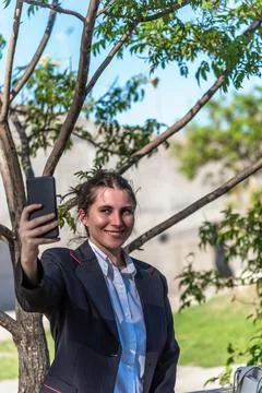 Executive woman smiling while taking selfies with her mobile phone outdoors. Stock Photos