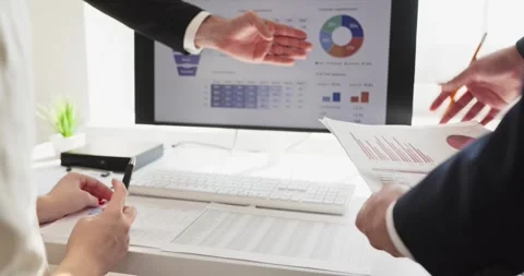 Executives discussing accounting charts and printed reports by computer screen Stock Footage 336006909