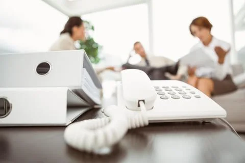Executives with land line phone and folders in foreground Stock Photos