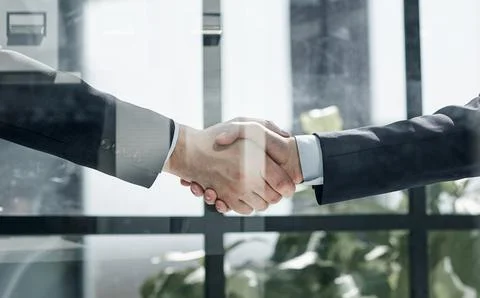 Executives shaking hands in front of their manager and a colleague Stock Photos