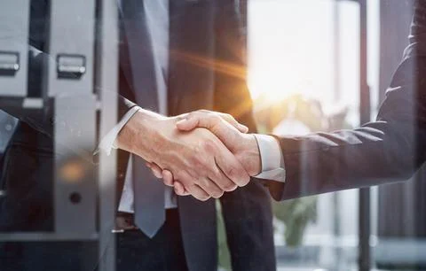 Executives shaking hands in front of their manager and a colleague Stock Photos