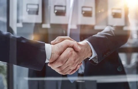 Executives shaking hands in front of their manager and a colleague Stock Photos