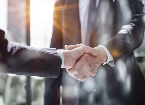 Executives shaking hands in front of their manager and a colleague Stock Photos