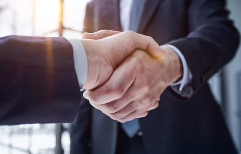 Executives shaking hands in front of their manager and a colleague Stock Photos