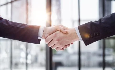Executives shaking hands in front of their manager and a colleague Stock Photos