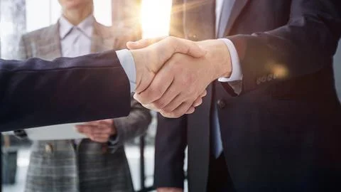 Executives shaking hands in front of their manager and a colleague Stock Photos