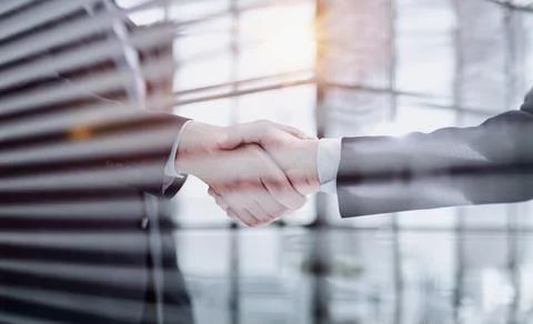Executives shaking hands in front of their manager and a colleague Stock Photos