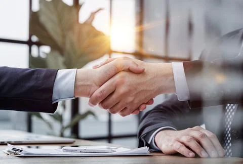 Executives shaking hands in front of their manager and a colleague Stock Photos