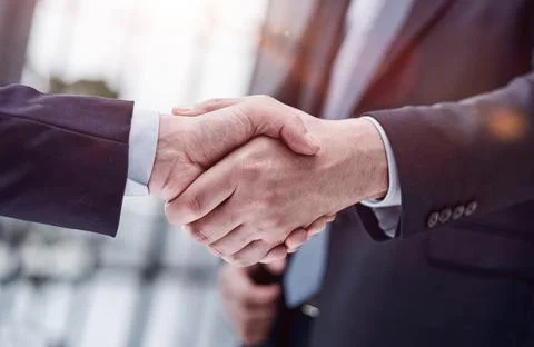 Executives shaking hands in front of their manager and a colleague Stockfoto's