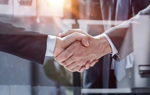 Executives shaking hands in front of their manager and a colleague 스톡 사진