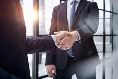 Executives shaking hands in front of their manager and a colleague Stock Photos