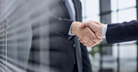 Executives shaking hands in front of their manager and a colleague Stock Photos