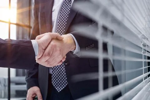 Executives shaking hands in front of their manager and a colleague Stock Photos