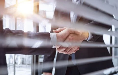 Executives shaking hands in front of their manager and a colleague Stock Photos
