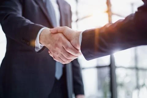 Executives shaking hands in front of their manager and a colleague Stock Photos