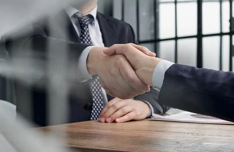 Executives shaking hands in front of their manager and a colleague Stock Photos