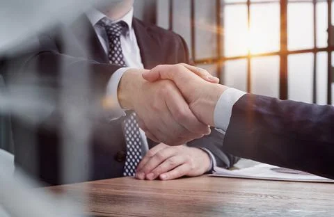 Executives shaking hands in front of their manager and a colleague Stock Photos