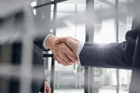 Executives shaking hands in front of their manager and a colleague Stock Photos