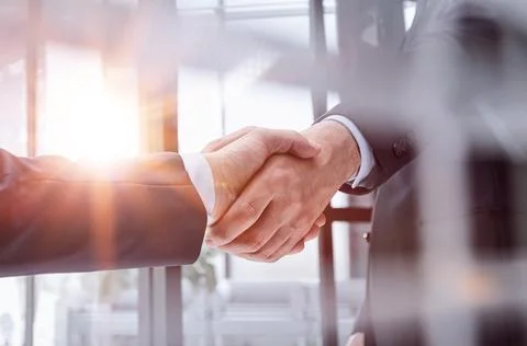 Executives shaking hands in front of their manager and a colleague Stock Photos