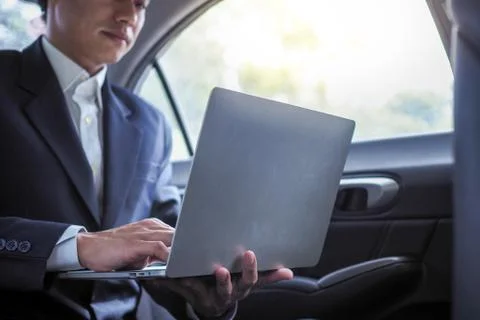 Executives use laptops to work while traveling and sitting inside the car. Foto stock