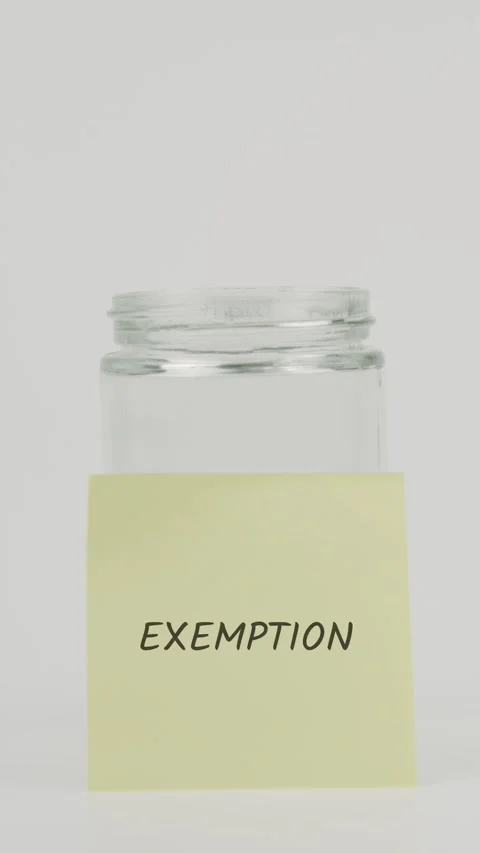 Exemption text or word on yellow sticky note attached to glass jar with hand Stock Footage 311729083