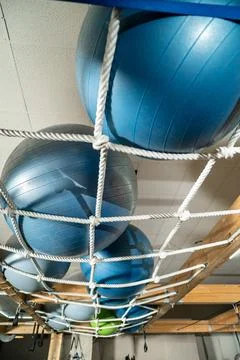 Exercise balls storing in rope net gym ceiling rack Stock Photos