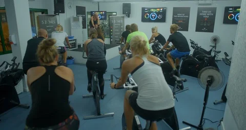 An exercise bike class lookig towards the instructor for leadership. Video stock 85535605
