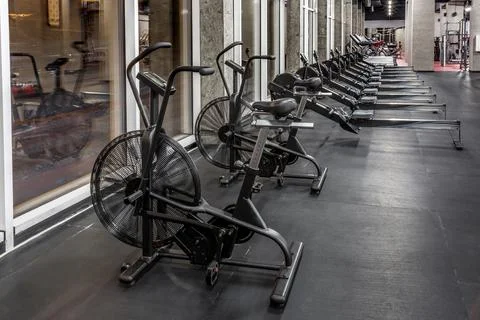 Exercise bikes, rowing machines and treadmills by window in spacious, empty gym Stock Photos
