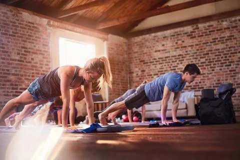 Exercise class practicing plank pose in gym studio Stock Photos