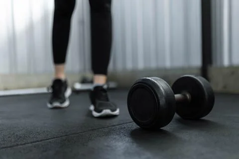 Exercise concept The black rubber coated round dumbbell lying on the gym grou Stock Photos