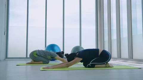 Exercise concept. A group of women practicing balasana exercises with a teach Stock Footage 143355702