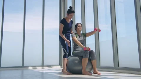 Exercise concept. Personal trainer helping woman working with heavy dumbbells Stock Footage 141014412